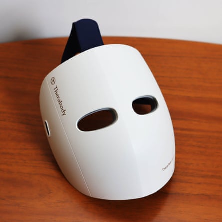 A white Theraface light therapy face mask device rests on a wooden table
