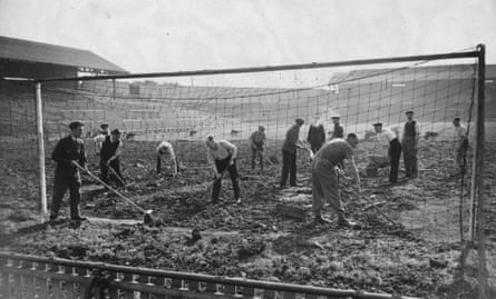 Volunteers clear debris from Millwall’s pitch after an air raid
