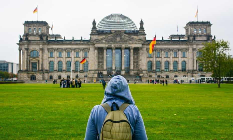 Young woman with backpack looking at Bundestag building in Berlin. 