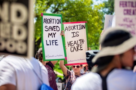 People hold signs that read 'abortion saved my life' and 'abortion is healthcare' at a rally