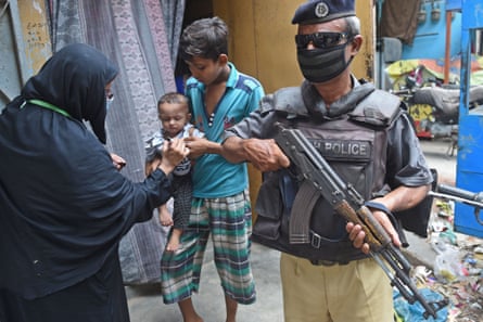 A policeman guards a health worker in Karachi. After the shooting of a policeman last month in Chaman, officers in the area are now reluctant to protect female polio workers.