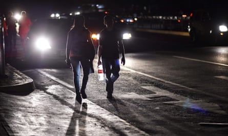A couple walks along a street in darkness.