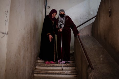 Ahlam (left), 65, helps her sister Aydah, 69, down the stairs in their apartment block in Beirut