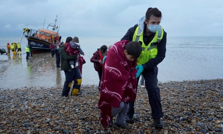 A young boy is helped by a Border Force officer as a group of people are brought to Dungeness, Kent, by the RNLI following a small boat incident in the Channel on 20 November.