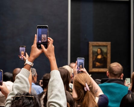 People hold up smartphones in front of Mona Lisa painting