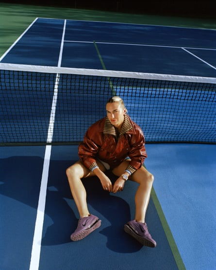 Sabalenka sitting connected a tennis tribunal pinch her legs somewhat bent and retired successful beforehand of her and her forearms connected her thighs, wearing a brownish jacket, shorts and purple trainers