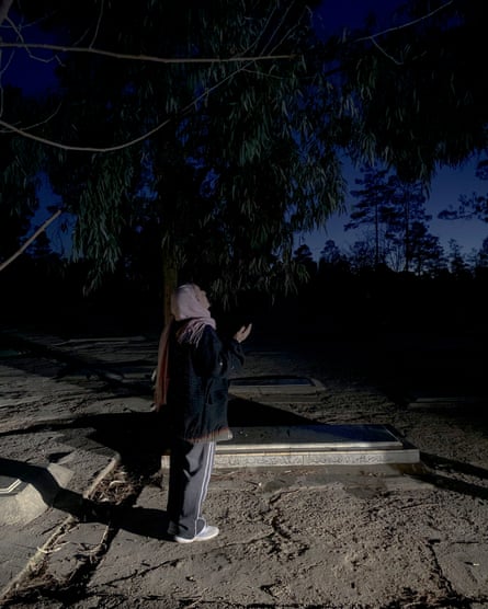 An elderly woman prays and weeps at the Behesht-e Zahra cemetery, Tehran