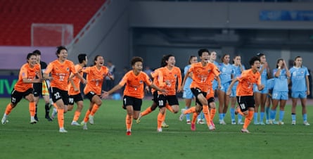 The Wuhan Jiangda players race towards their goalkeeper Chen Chen after their penalty shootout victory.