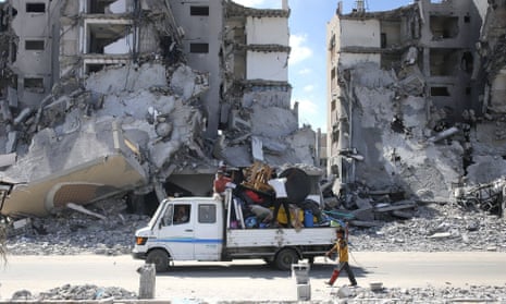 A flat-bed truck overflowing with a family's belongings as a boy walks alongside it