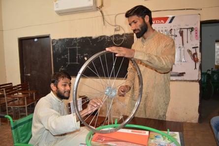 Usman Malik, left, is taught how to build wheelchairs by Muhammad Kashif on a Society for Special Persons’ six-month training course.
