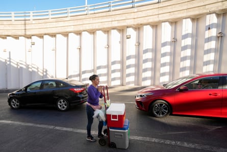 A woman stays in the shade as she sells food and drinks to drivers waiting to cross the border to Calexico, California, on 20 July, in Mexicali, Mexico. She says she only works till about 10am due to the extreme heat, idling cars and hot pavement.