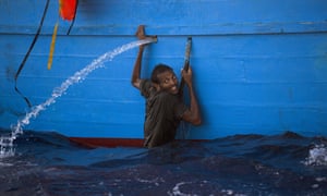 A man holds himself to the side of a boat