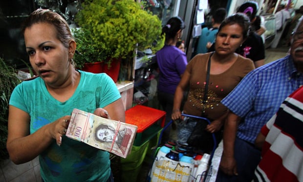 A woman shows a wad of 100-bolivar bills in San Cristobal, Venezuela