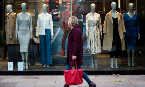 A woman walks past mannequins in a Reiss store