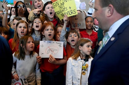children hold signs against gun violence and shout at a man in a suit