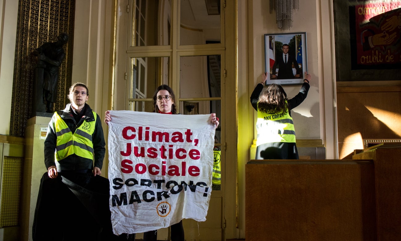 Climate crisis activists remove a portrait of Emmanuel Macron in Paris.
