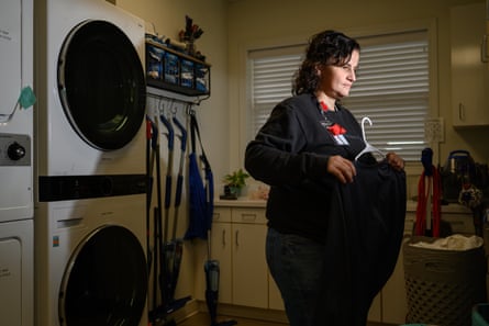 A woman in front of a washer and dryer puts a top on a hanger