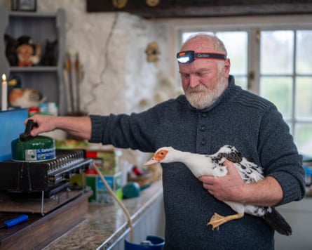 Roger Gillespie holding a duck under one arm and a kettle in his other hand