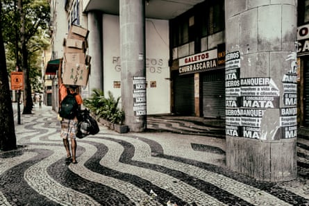A man walks next to a poster in Rio Centro that reads: ‘Bankers, respect the lives of workers and customers – coronvirus kills'