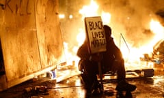 during a demonstration in Oakland, California following the grand jury decision in the shooting of Michael Brown in Ferguson, Missouri<br>A demonstrator sits in front of a street fire during a demonstration following the grand jury decision in the Ferguson, Missouri shooting of Michael Brown, in Oakland, California November 25, 2014. The grand jury decided on Monday not to indict a white police officer over the fatal August shooting of an unarmed black teenager. REUTERS/Stephen Lam (UNITED STATES - Tags: CIVIL UNREST POLITICS CRIME LAW TPX IMAGES OF THE DAY)