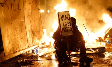 A demonstrator sits in front of a street fire following the grand jury decision in the Ferguson, Missouri shooting of Michael Brown, in Oakland, California, 25 November 2014.