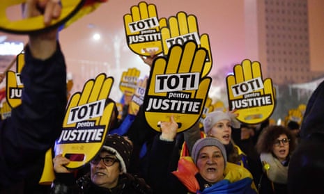 People hold placards reading ‘All for justice’ during a protest in Bucharest