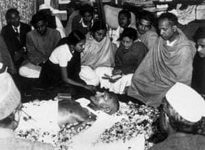 The niece of Mahatma Gandhi places petals on his brow as he lies in state at Birla House, Delhi, in February 1948