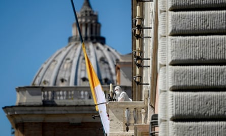 A person in protective gear stands at the balcony of a Vatican building on Via della Conciliazione in Rome