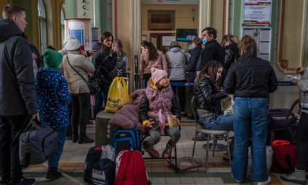 Refugees from Ukraine stand in line for free train tickets in the hall of the main railway station in Przemysl, southeastern Poland, near the Polish-Ukrainian border on March 26