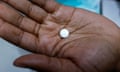 Young Black hand holds round white pill
