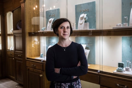 Charlotte Gatward looks into the camera; jewellery is displayed in the background