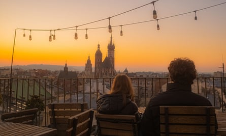 A couple admires a beautiful panoramic view at sunset on the observation terrace of a cafe in the old European city of Krakow.