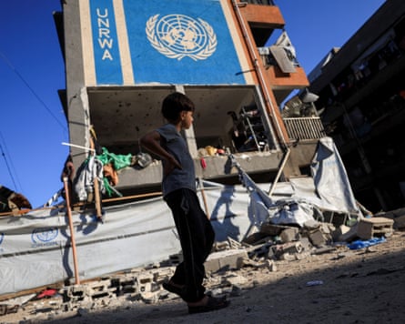 A boy walks near a building bearing a large Unrwa sign