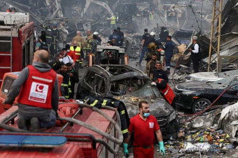 emergency responders work at the site of an airstrike amidst rubble and burnt out cars