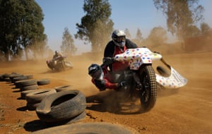 A sidecar racer hangs off the side of a motorbike during a race at the Walkerville Dirt Oval in Johannesburg, South Africa