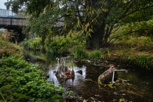 A photograph by Merlin Daleman of shopping trolleys dumped in a river near a social supermarket run by Around Again Charity, Birmingham, October 2022. 