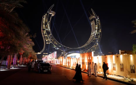 Welcome to Lusail: Lego-city of the gods and one of the strangest places on earth | World Cup 2022 15 Locals walk past a painted facade made to look like old houses, erected to hide building works going on behind, with in the background the Katara Towers on the seafront in Lusail which houses two luxury hotels, where many FIFA officials are staying.