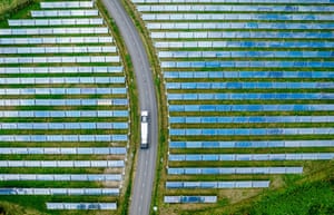 An aerial view of a bus driving through a solar farm