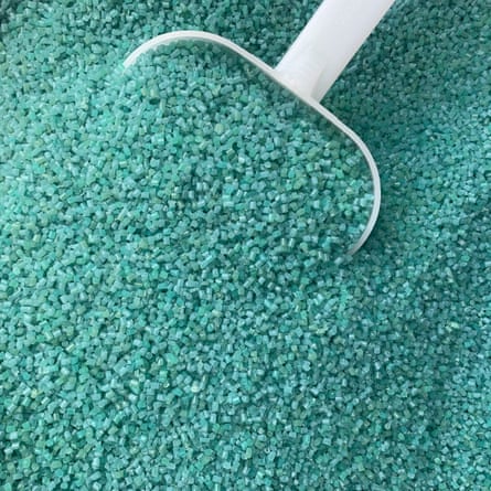 A plastic scoop among loads of small blue-green beads