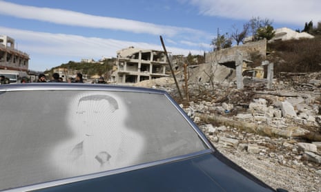 An image of Bashar al-Assad is seen on a car parked in front of damaged buildings in the town of Rabiya, Syria