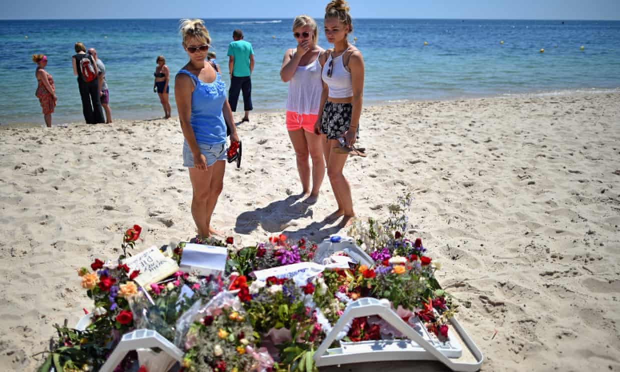 Holidaymakers view flowers left on Marhaba beach in Sousse.