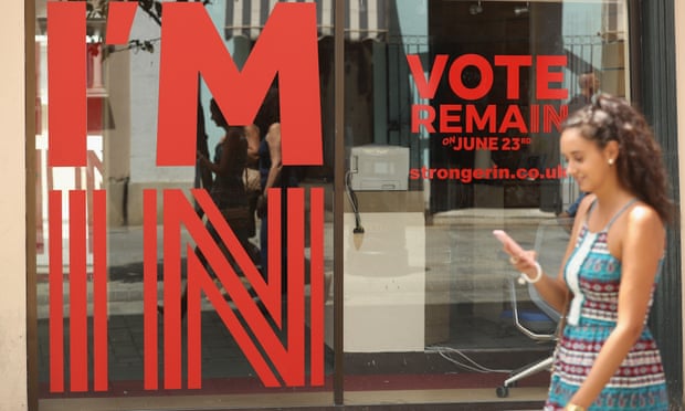A young woman walks past a Gibraltar storefront sign urging people to vote to remain. 