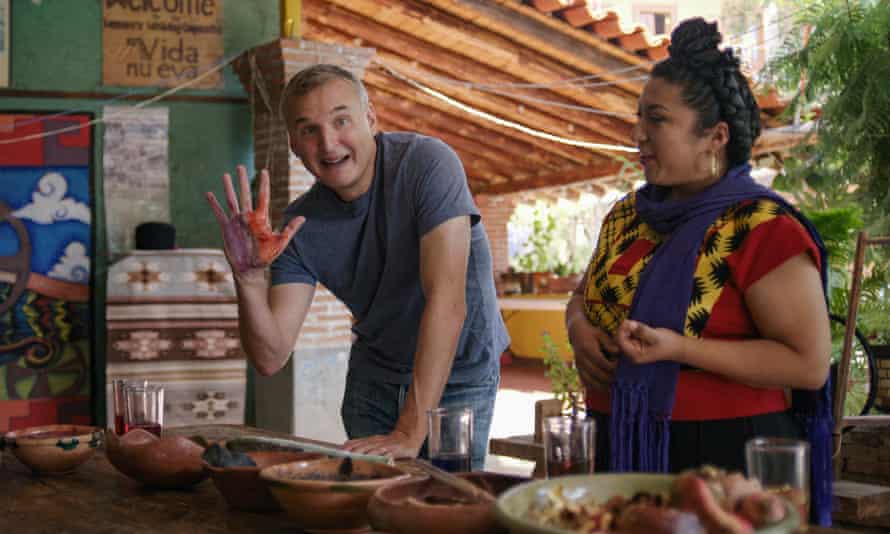 Phil Rosenthal holds up his hand coloured with dye or paint, before a table laden with food