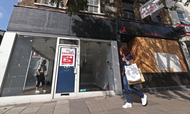 A woman walks past two closed businesses on Upper Street in Islington, north London