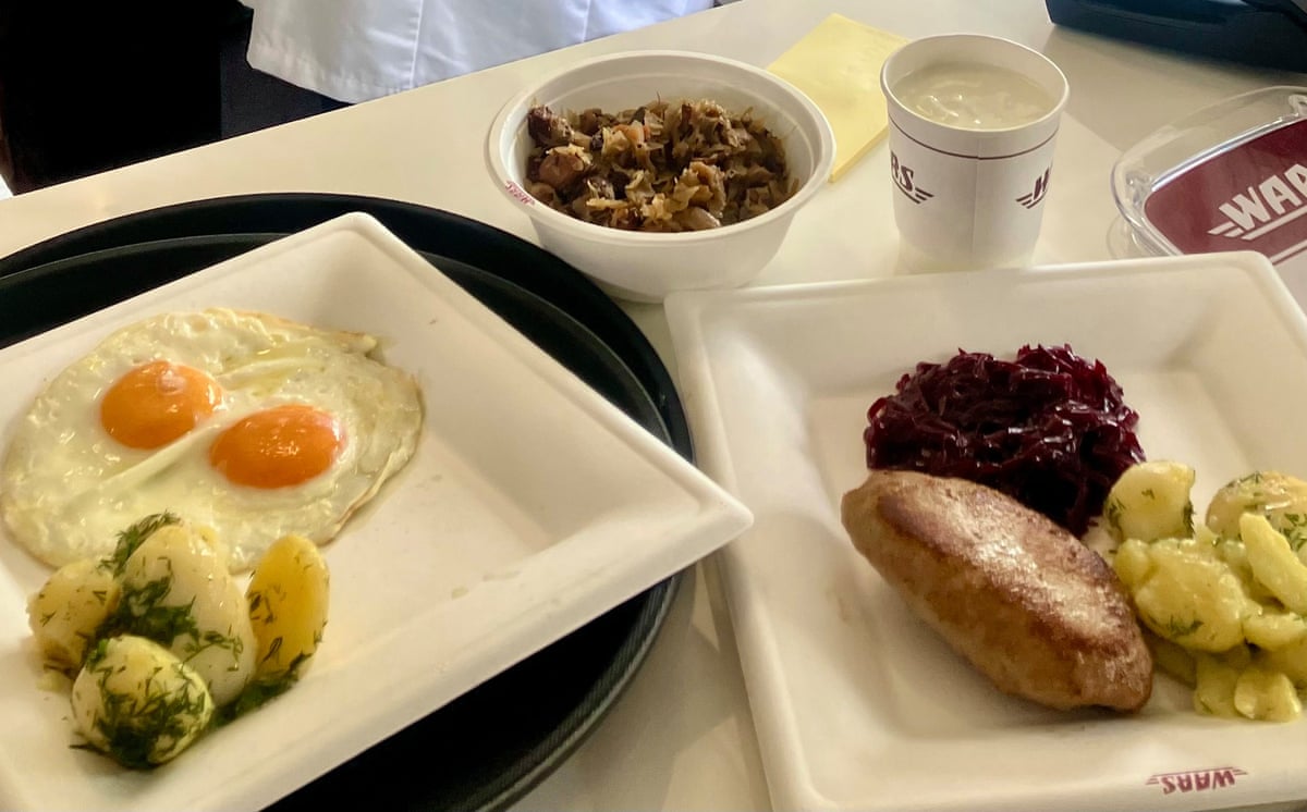 Plates of food with potatoes, egg and chicken that are served in the dining car
