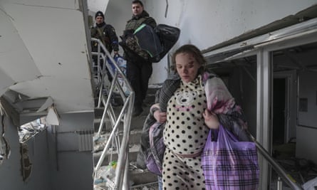 An injured pregnant woman walks downstairs in the damaged by shelling maternity hospital in Mariupol, Ukraine, Wednesday, March 9