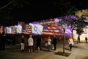 People take photographs of the US and Israeli flags projected as a show of unity on to the walls surrounding Jerusalemâs Old City