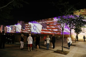 People take photographs of the US and Israeli flags projected as a show of unity on to the walls surrounding Jerusalemâ€™s Old City