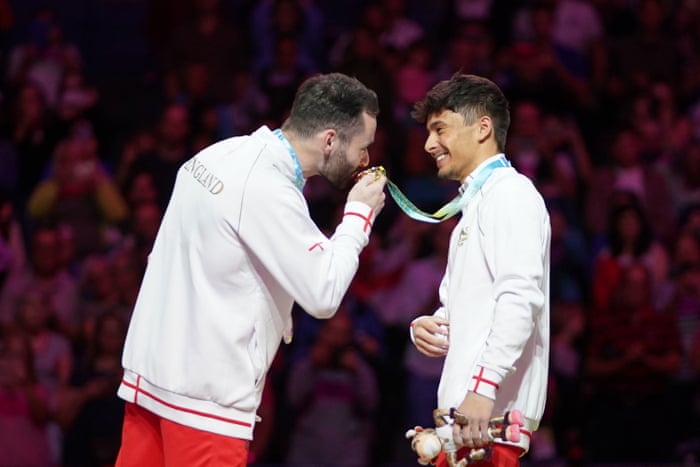 James Hall gives Jake Jarman’s gold medal a little kiss.