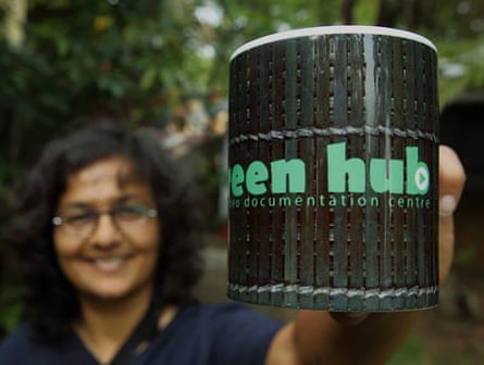 Rita Banerji smiles and holds up a Green Hub branded mug to the camera